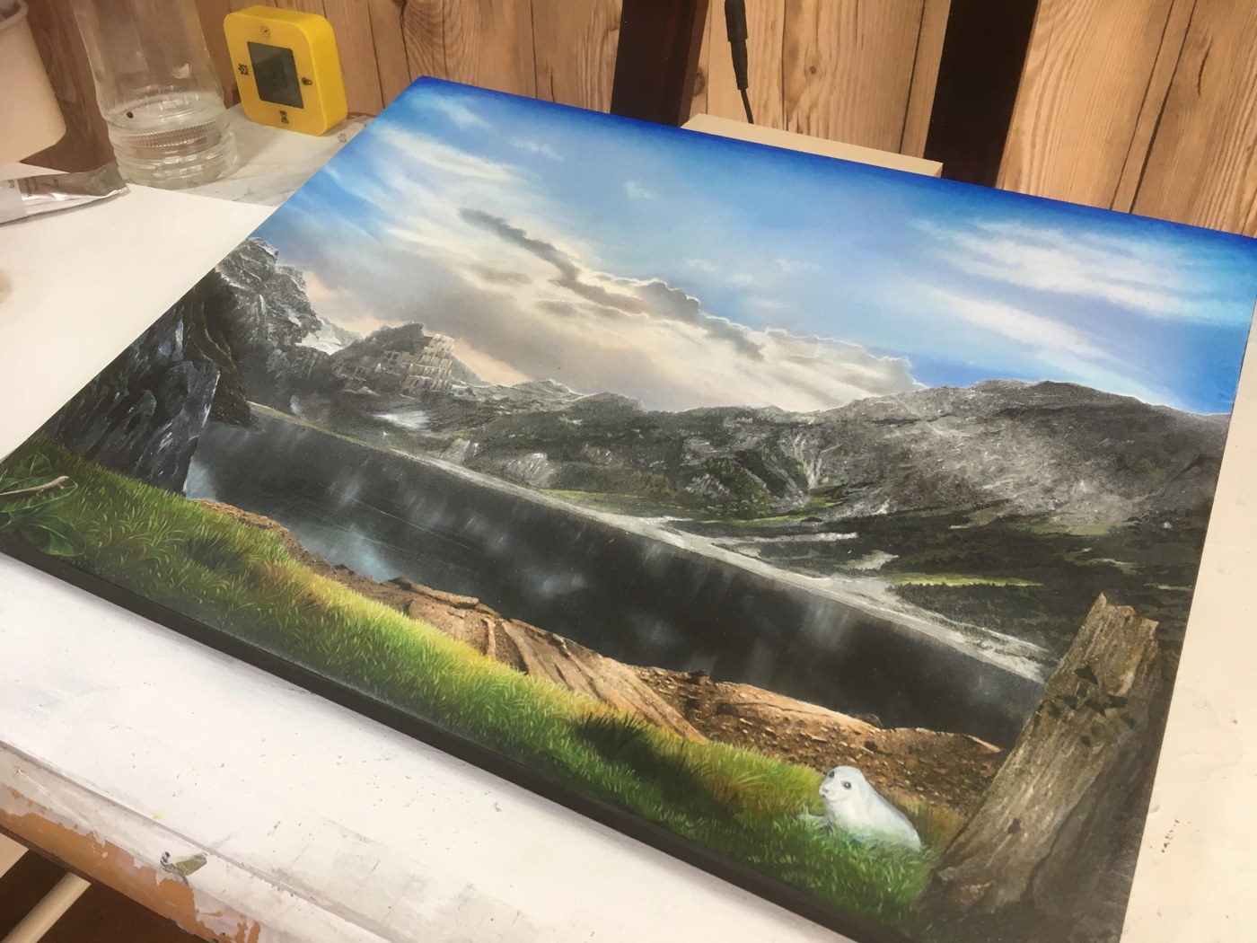 岡部遼太郎のアクリル画作品「刻の塔」。山に囲まれた湖と草地の風景